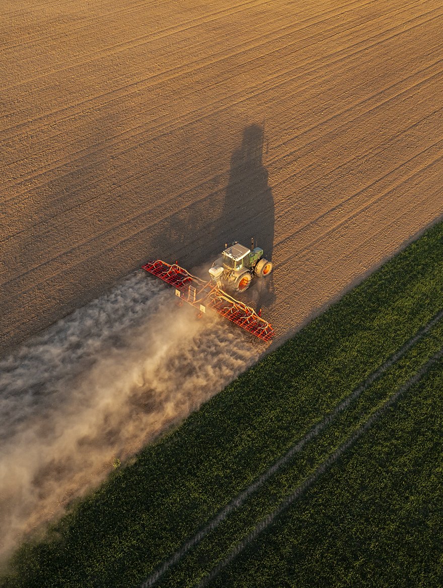 Moderner Traktor im Erntefeld bei Sonnenuntergang
