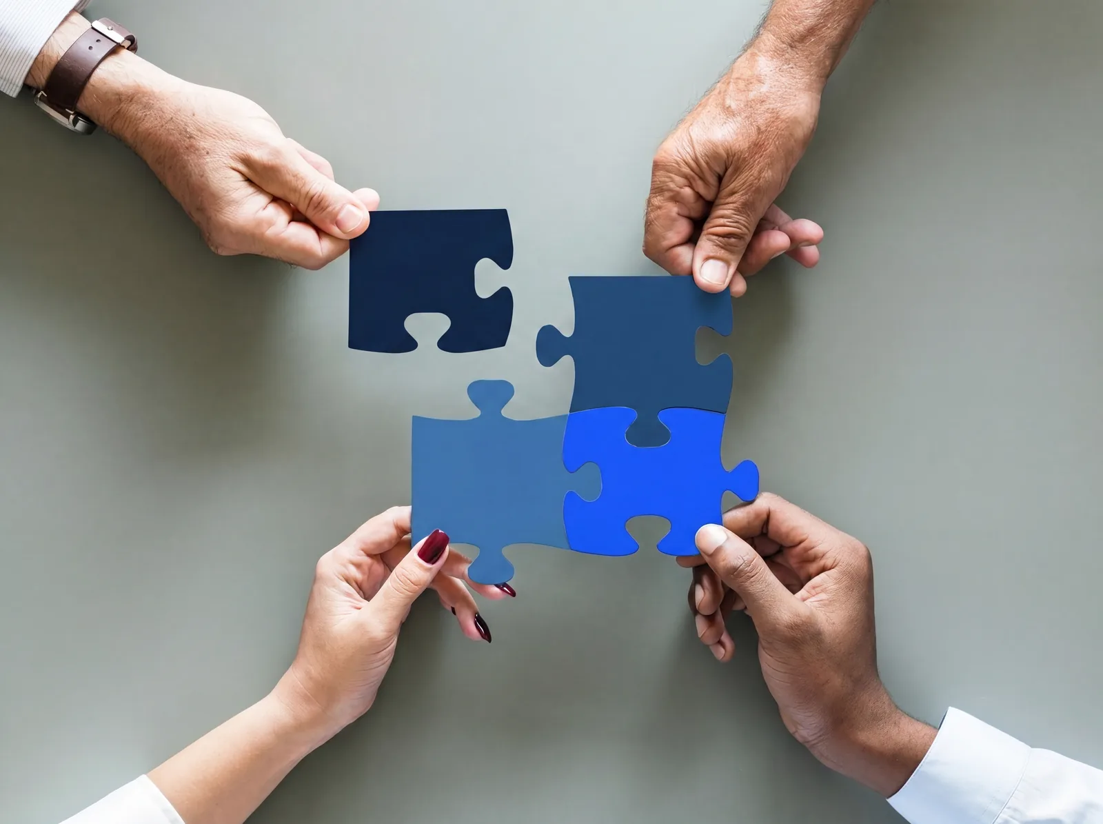 Vier Hände fügen blaue Puzzleteile zusammen — partnerschaftliche Zusammenarbeit bei der Beresa Leasing